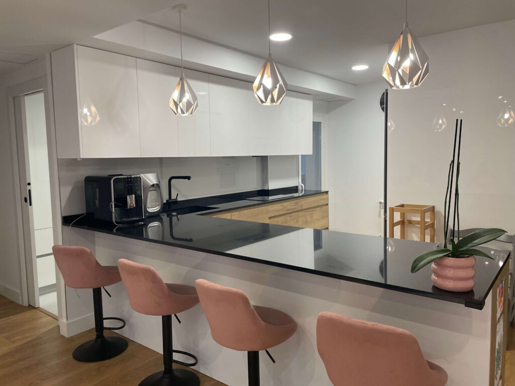 cocina de diseño exclusivo Madrid con barra alta encimera negra y taburetes rosas