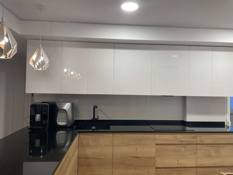 cocina a medida Madrid con isla de madera y encimera negra iluminación colgante